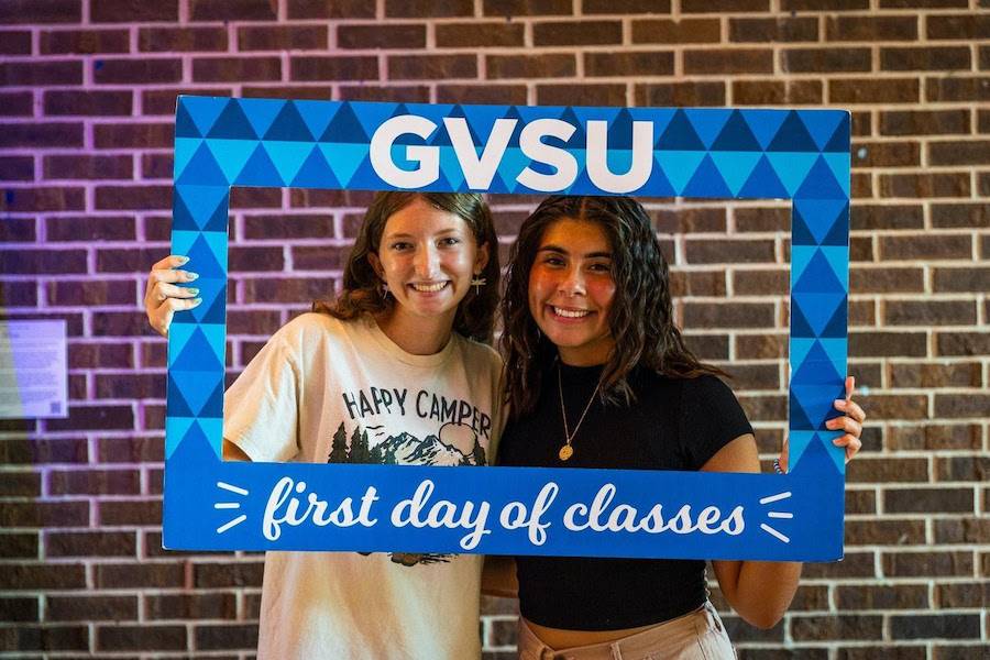 Two girls holding up a frame that says GVSU First Day of Classes